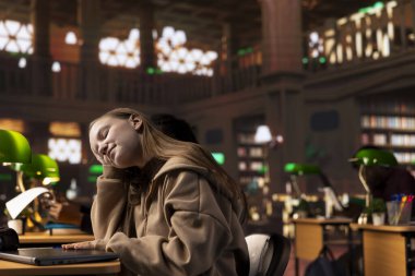 Araştırmasını yaparken uyanık kalmak için çabalayan genç bir öğrenci üniversite diplomasını almak için kütüphanedeki bekarlık kağıdına yazı yazıyor. Kız sertifika için çok çalışıyor..