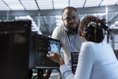 Veri merkezi tesisinde meslektaşımla birlikte çalışan bir sistem yöneticisi farklı iş yükleri için hesaplama kaynakları sağlıyor. Yapay zeka süper bilgisayarlarını izlerken iş arkadaşıyla konuşan bilişim uzmanı.