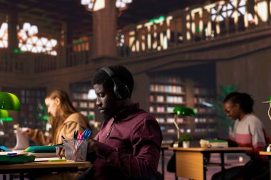 Afrikalı Amerikalı erkek öğrenci okul ödevinde yardımcı olmak için ortam odaklı müzik kullanır, üniversite veritabanındaki akademik kitaplar ve diğer kaynaklardan alıntılar toplar. Araştırma koleksiyonu.