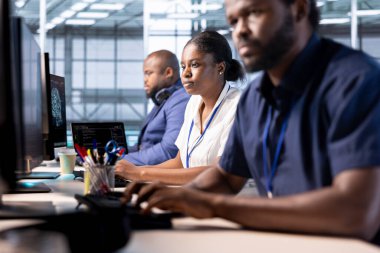 Veri merkezi mühendislerinden oluşan bir ekip yazılım uygulamaları için teknik belgeler hazırlıyor. Sunucu merkezinde çalışan Afrikalı Amerikalı bilgisayar bilimcileri veritabanlarını koruyorlar.