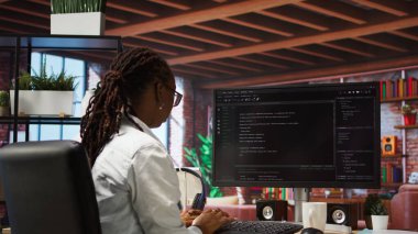 Programcı PC 'ye kod yazar, komutları girer, betiği çalıştırır. Afrika kökenli Amerikalı bilişim uzmanı uygulamalarda hata düzeltme, yeni özellikler ekleme, kamera A