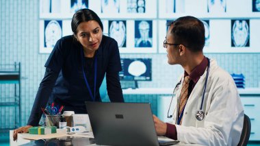 Hintli profesyonel sıhhiyeci hemşiresiyle beşlik çakıyor. Tıp alanında uzman. Hastane personeli röntgen ve MR sonuçlarını inceliyor ve tanı raporuna odaklanıyor. Kamera A.