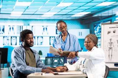 Afrikalı Amerikalı doktor, erkek bir hastanın nabzını ölçmek için akıllı saatini kullanıyor. Rutin kontrolde modern dijital cihazlar. Bir fitness takip cihazı aksesuarıyla kalp atışı ölçüsü.