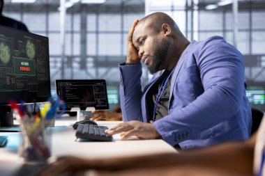 Veri merkezindeki kızgın mühendis PC ekranından bildirimi reddediyor, bilgisayar korsanları tarafından kilitlendikten sonra fidye virüsü kullanarak önemli dosyalara erişmeye çalışıyor, avuç içi hareketleri yapıyor.
