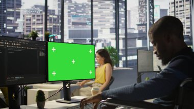 Kapsayıcı iş yerinde engelli bir adam yeşil ekran bilgisayarında makine öğrenme teknolojisiyle çalışıyor. Tekerlekli sandalyedeki belden aşağısı felçli Afrikalı Amerikalı bilişim uzmanı model bilgisayar ve kamera B üzerinde çalışıyor.