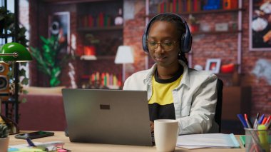 Ev ofisteki klavyeye yazarken müzik dinleyen, e-posta yazan bir tele-işçi. Uzaktan kumandalı çalışan kulaklık takıyor dizüstü bilgisayar kullanıyor, proje işlerini bitiriyor, kamera B