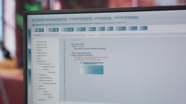 Merkez ofisteki mühendis bilgisayar monitöründe UI 'ya bakıyor, programlama kodunu yazıyor ve çalıştırıyor. Modern apartman, kamera B 'de kod yazıp test etmek için kodlama uygulaması kullanan kişiyi kapat