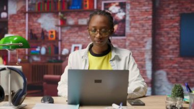 Ofisteki bilgisayarla e-posta yazan mutlu bir tele-işçi portresi. Not defterinde yazan neşeli uzaktan çalışan, bitirilmiş proje evraklarını teslim etmek için belge düzenleyen, kamera B