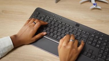 Ofis masasında kahve fincanının yanındaki klavyeye yazı yazan kişi, yakın çekim. Uzaktan kumandalı apartman çalışanı bilgisayarın çevre tuşlarına basıyor, veri giriyor, kamera A