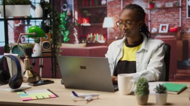 Evdeki ofis masasında çalışan, kahve içen, internette gezinen, bilgi toplayan biri. İş için veri bulmak için arama motorlarını kullanırken sıcak içecekten hoşlanan kadın, kamera A