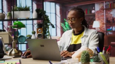 Evde boş zamanların tadını çıkaran, abur cubur yiyen, dizüstü bilgisayardan arkadaşlarına mesaj atan biri. Afrika kökenli Amerikalı bir kadın kruvasandan hoşlanıyor, sosyal ağ sitesinden arkadaşlarıyla konuşuyor, not defteri, kamera A kullanıyor.