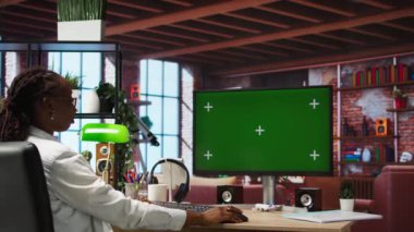 E-posta yazmak için merkez ofisteki yeşil ekranlı bilgisayarı kullanan bir tele-işçi. Bilgisayarın klavyesine yazı yazan, nihai proje evraklarını teslim etmek için belge düzenleyen uzaktan çalışan bir işçi, kamera A