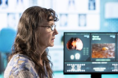 Yaşlı kadın doktoruyla hastalık teşhisi ve iyileşme planı hakkında konuşuyor. Bilgisayardaki röntgen sonuçlarına bakıyor. Uzman, sağlık sigortası ile kadın hasta toplantısı.