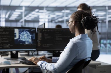 Sunucu merkezindeki bilgisayarda yazan kadın yapay zeka yazılımı kullanarak veri merkezinin enerji tüketimini izliyor. Sunucu odasında yapay zeka teknolojisi kullanarak süper bilgisayarları yöneten mühendis.