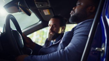 Adam araba alıyor, her şeyin düzgün çalıştığından emin olmak için test sürüşü yapıyor. Afrikalı Amerikalı sürücü aracı inceliyor, özelliklere ve muhtemel kusurlara bakıyor, kamera B