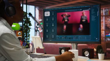 AI yazılımı kullanan bir kadın metni fotoğrafa dönüştürüyor, kahve içiyor ve müzik dinliyor. Konforlu evdeki Afrikalı Amerikalı insan PC, Kamera A 'da görüntü üretken modeller için metin kullanıyor.