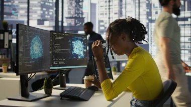 Ofisteki çalışanlar mesai sırasında esniyorlar. Bilgisayardaki yapay zeka yazılımına bakarken yorgun hissediyorlar. Yorgun afrikalı amerikan yapay zeka şirketi çalışanı çalışma alanında uykulu, kamera B