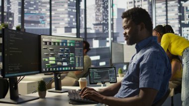 İşteki sistem yöneticisi verileri işleyebilen ve analiz edebilen makine öğrenme modelleri yaratıyor. Ofisteki Afrika kökenli Amerikan bilişim uzmanlarının bilgisayar, kamera B kullanarak programlarını kapat.