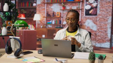 Evdeki ofis masasında çalışan, kahve içen, internette gezinen, bilgi toplayan biri. İş için veri bulmak için arama motorlarını kullanırken sıcak içecekten hoşlanan kadın, kamera B