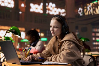 Üniversite öğrencisi video görüşmesi yoluyla uzaktan ders sırasında dikkat çekiyor kampüsteki üniversite kütüphanesindeki Webinar tartışmasından notlar alıyor. Öğrenci çevrimiçi kursa katıldı.