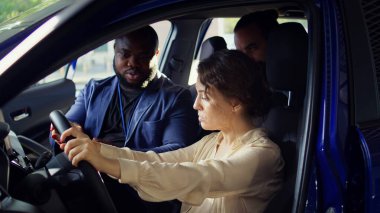 Deneme sürüşü sırasında araçtaki sorunları gözlemledikten sonra galeri satıcısıyla tartışan bir adam. Kocasının yanındaki direksiyondaki üzgün kadın, araba kullandıktan sonra fark edilen endişeleri anlatıyor, kamera B