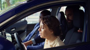 Satıcı araba almadan önce müşterilerle test sürüşü yapıyor, güvenlik özelliklerinden bahsediyor. Çift yeni bir araç alıyor, nasıl hissettirdiğini değerlendiriyor, kamera B.