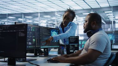 Veri merkezinde iş arkadaşıyla birlikte çalışan bir sistem yöneticisi farklı iş yükleri için hesaplama kaynakları sağlıyor. Yapay zeka süper bilgisayarlarını, kamera B 'yi izlerken iş arkadaşıyla konuşan bilişim uzmanı.