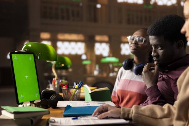 Genç öğrenci sınav hazırlıkları için araştırma yaparken, güvenilir akademik kaynaklardan eğitim bilgileri okurken, modelleme sergisi kullanır. Öğrenci notlarını ders kitabında tamamlar..