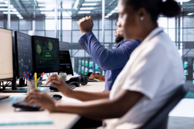 Sunucu çiftliğindeki yönetici giriş izni aldıktan sonra kutlama yapıyor, hackerlar tarafından kilitlendikten sonra dosyalara erişmeyi başarıyor, fidye virüsü yazılımı kullanıyor, IT uzmanlarından yardım alıyor, el hareketi yapıyor.