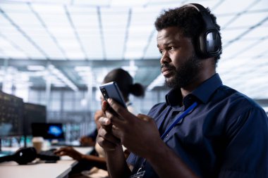 Veri merkezinde müzik dinleyen ve akıllı telefondan arkadaşlarına mesaj atan bir adam, hataların kökenini belirlemek için teşhis araçları kullanıyor. Bilgi işlem uzmanı sunucu odasında cep telefonu kullanarak kulaklık takıyor