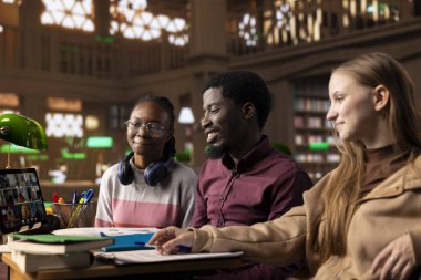 Kampüs kütüphanesinden çevrimiçi sınıf webinarlarına katılan çeşitli öğrenciler, lisans dereceleri üzerinde çalışırken uzak kurslara katılıyorlar. Enstitü içinde akademik araştırma.