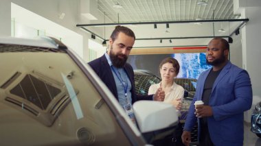 Araba satış temsilcisi bireylere ne tür bir araca yatırım yapacaklarına karar vermelerinde yardımcı oluyor. Showroom temsilcisi müşterilere doğru aracı seçmeleri için yardımcı oluyor, kamera B