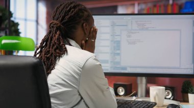 Ofiste bilgisayar monitöründen UI 'ye bakarken hayal kırıklığına uğrayan mühendis programlama kodunu düzgün çalıştıramadı. IT çalışanı kodlama uygulaması, kamera B kullanırken hata gördüğünde memnun değil