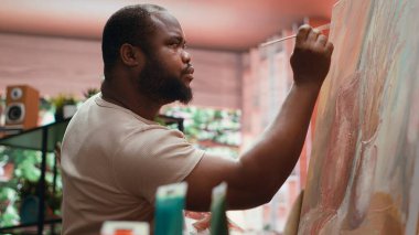 Yetenekli bir ressam palete renkli boyalar çizerek atölyesindeki resim tekniğiyle güzel, yaratıcı bir resim yaratıyor. Ressam suluboya karıştırıyor. Kamera A.