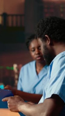 Geleceğin dikey video hemşireleri bir üniversite kütüphanesinde anatomi sınıfı notlarını inceliyor, dersleri gözden geçiriyor ve sınavlara hazırlanıyor. Siyahi tıp fakültesi öğrencileri tıp eğitimi için birlikte çalışıyorlar.