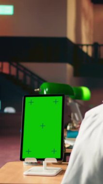 Dikey Video Genç Tıp öğrencisi krom anahtarın yanındaki sınavlar için araştırma yapıyor, yeşil lamba altında farmakoloji kağıtlarını inceliyor. Sınav hazırlıklarına ve tıp kariyerlerine odaklanıyorlar.