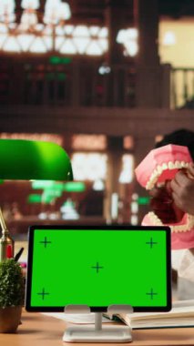 Dikey Video Erkek Diş Hekimliği öğrencisi, yapay ekranın yanında ağız hijyenini öğrenir ve plastik bir insan çene modeli üzerinde diş uygulamalarını öğrenir. Alim başarılı bir kariyer için dişleri inceliyor.