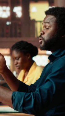 Dikey Video Koleji öğrencileri kampüs kütüphanesinde ders notlarını incelemek için çırpınıyor, bunalmış bir öğrenci endişeyle öğrenmeye çalışıyor. Erkek ergen notlarıyla ilgileniyor. Kamera B