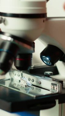 Dikey video araştırmacısı mikroskop altında mikroorganizmaları inceleyerek, mikrobiyoloji ve tıp bilimini okuyarak tezinin üzerinde çalışıyor. Bilimsel sınavlara odaklan. Kapat.