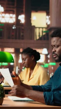 Dikey Video Afrikalı Amerikalı üniversite öğrencisi son dersten kalan teorik notları çalışmak için çabalıyor, sınava hazırlanmayı öğreniyor. Kampüs kütüphanesindeki sinirli genç.