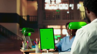 Genç tıp öğrencisi kroma anahtarının yanındaki sınavlar için araştırma yapıyor, yeşil bir lamba altında farmakoloji belgelerini gözden geçiriyor. Sınav hazırlıklarına ve tıp kariyerlerine odaklanıyorlar. Kamera B.