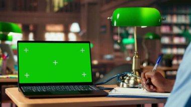 Afrikalı Amerikalı erkek hemşire, başarılı bir tıp kariyeri için akademik veritabanını kullanarak, bir üniversite kütüphanesinde yeşil ekranın yanında anatomi ders kitapları okuyor. Tıp fakültesi. Kamera B.