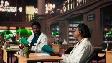 İki tıp fakültesi öğrencisi, izlenim ve fikir alışverişinde bulunarak geleneksel bir kütüphanede çalışmalarına odaklanıyor. Öğrenciler tıbba ve sağlık hizmetlerine büyük bağlılıklarını gösteriyorlar. Kamera A.