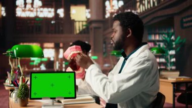 Erkek diş hekimliği öğrencisi, yapay ekranın yanında ağız hijyenini öğreniyor, bir plastik insan çene modeli üzerinde diş uygulamalarını öğreniyor. Başarılı bir kariyer için dişleri inceliyor. Kamera A.