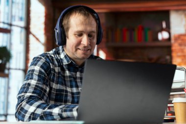 İşte gülümseyen bir çalışan dizüstü bilgisayarla sosyal medyada komik videolar izliyor. Keyifli çalışanlar, sosyal ağ web sitesini kullanırlar, içerikten keyif alırlar, ofiste kaytarırlar.