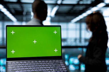 Bilgisayar bilimcilerinin veri merkezinde sunucuları denetleyen, ağ topolojilerini güncelleyen yeşil ekran laptopuna odaklan. IT profesyonellerinden oluşan bilişim ekibinin yanındaki not defterini kapat