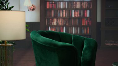 Saf yeşil kadife sandalyeleri, kitaplıkları ve sakinleştirici ahşap dekorları olan boş, zarif bir psikoterapi ofisi. Danışmanlık oturumları, istişareler veya terapist müvekkil tartışmaları için mükemmel bir alan.