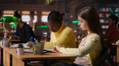 Kütüphanede kitap okuyan genç kızlar zorunlu edebiyat üzerine odaklanmak ve eğitim sırasında akademik müfredat hakkında bilgi kazanmak için. Genç alimler konferans görevlerine odaklanıyor. Kamera B.