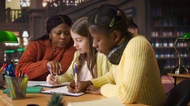 Öğrencilere sınıf ödevleri ve akıl hocalığı konusunda yardım eden, akademik eğitim veren ve okul ödevlerini geçmelerine yardımcı olan bayan öğretmen. Hoca özel ders veriyor. Kamera A.
