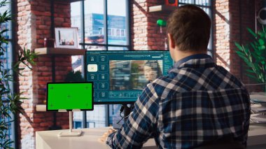 Merkez ofisteki adam yapay zeka programını kullanarak metni izole ekran tabletinin yanındaki videolara dönüştürüyor. Bilgisayar ve krom anahtar aygıtında video üretici modeller için metin kullanan kişi, kamera A